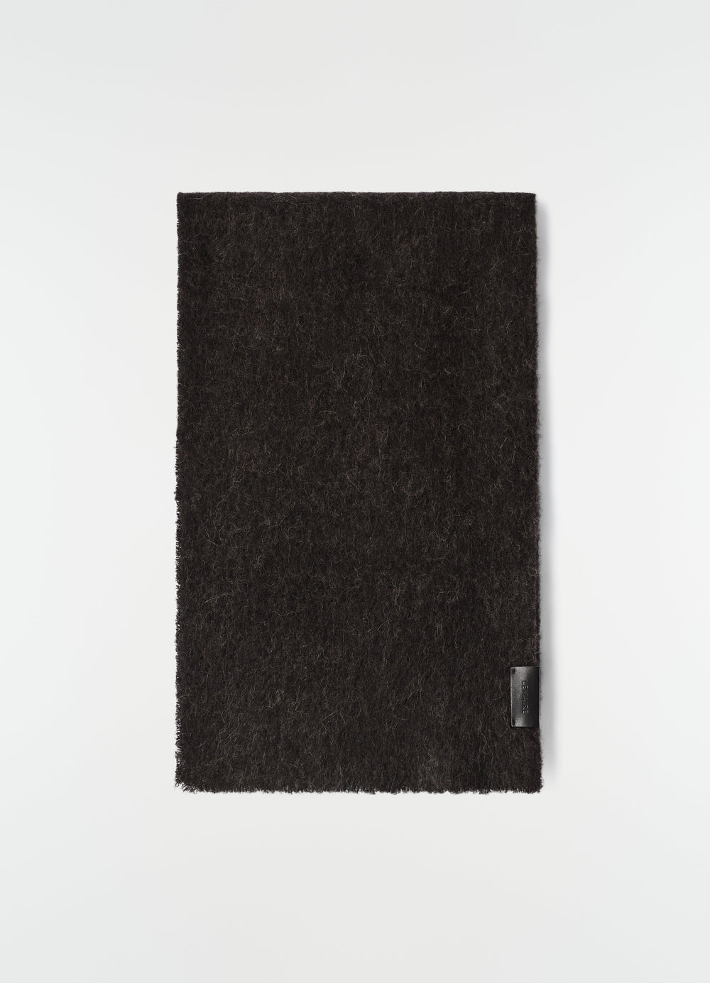 Fluffy black alpaca wool blend scarf by LEMAIRE flat lay with leather logo patch on plain white background