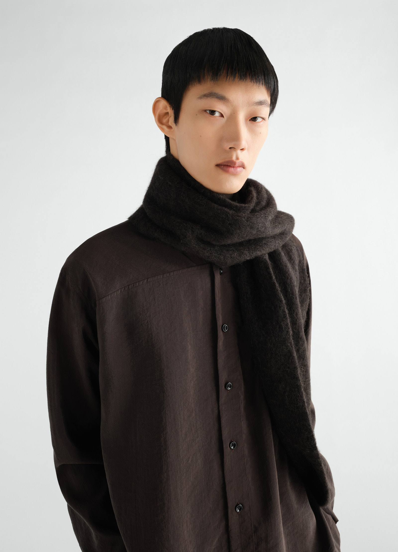 Fluffy black alpaca wool blend scarf by lemaire worn by model front view with brown shirt