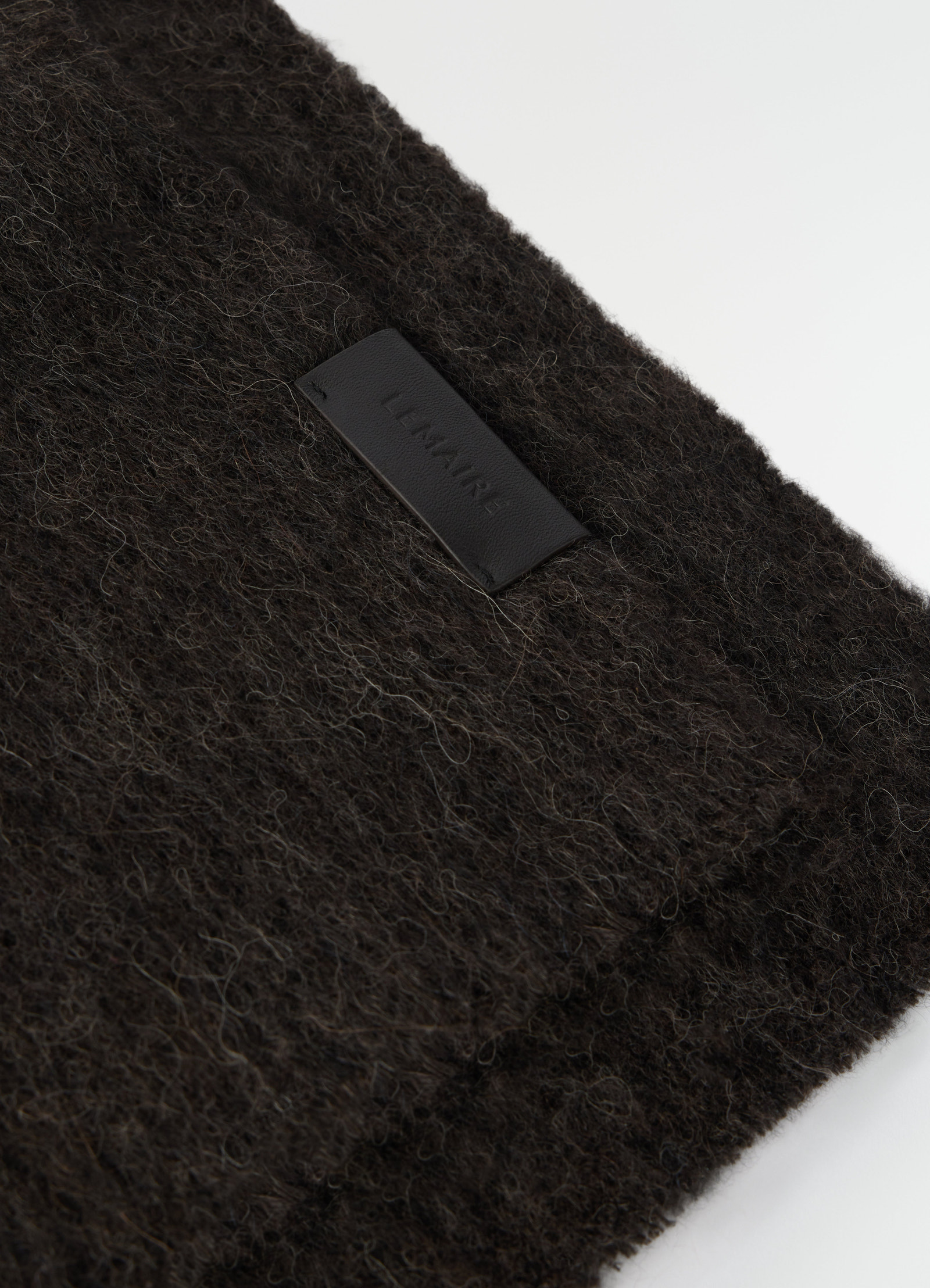 Fluffy dark brown alpaca wool blend scarf with black leather lemaire logo patch close-up detail