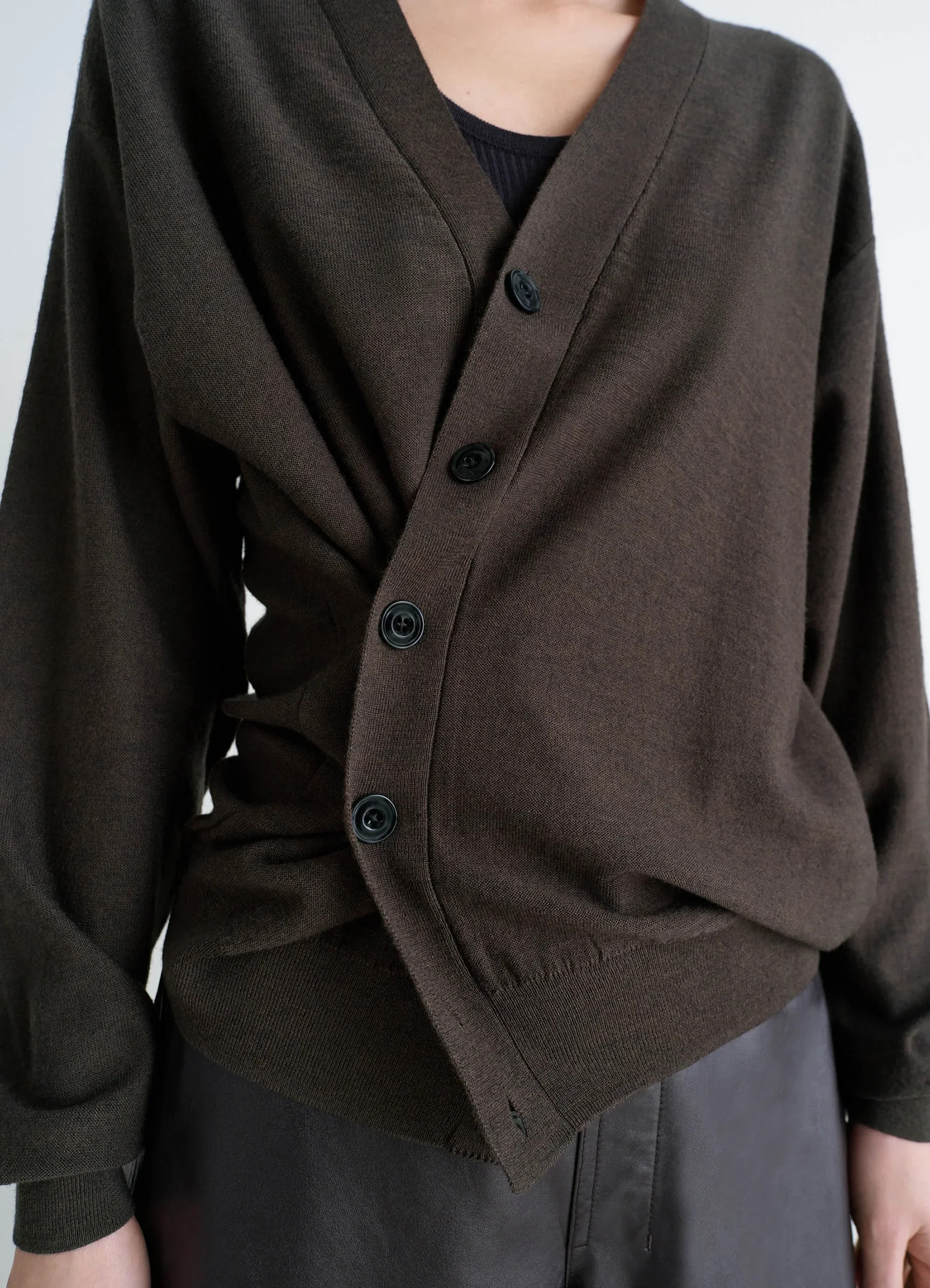 Lemaire relaxed twisted cardigan in knitted merino wool, model shot, close-up side view asymmetrical draped wrap