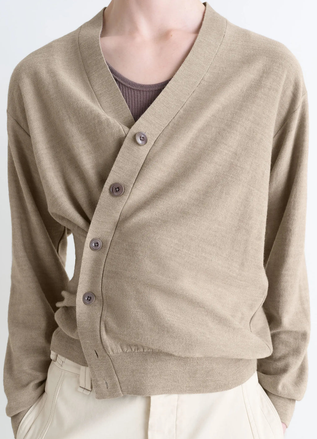 Lemaire Relaxed Twisted Cardigan in Light Beige Blended Merino Wool, model shot, mid-torso close-up asymmetrical drape detail