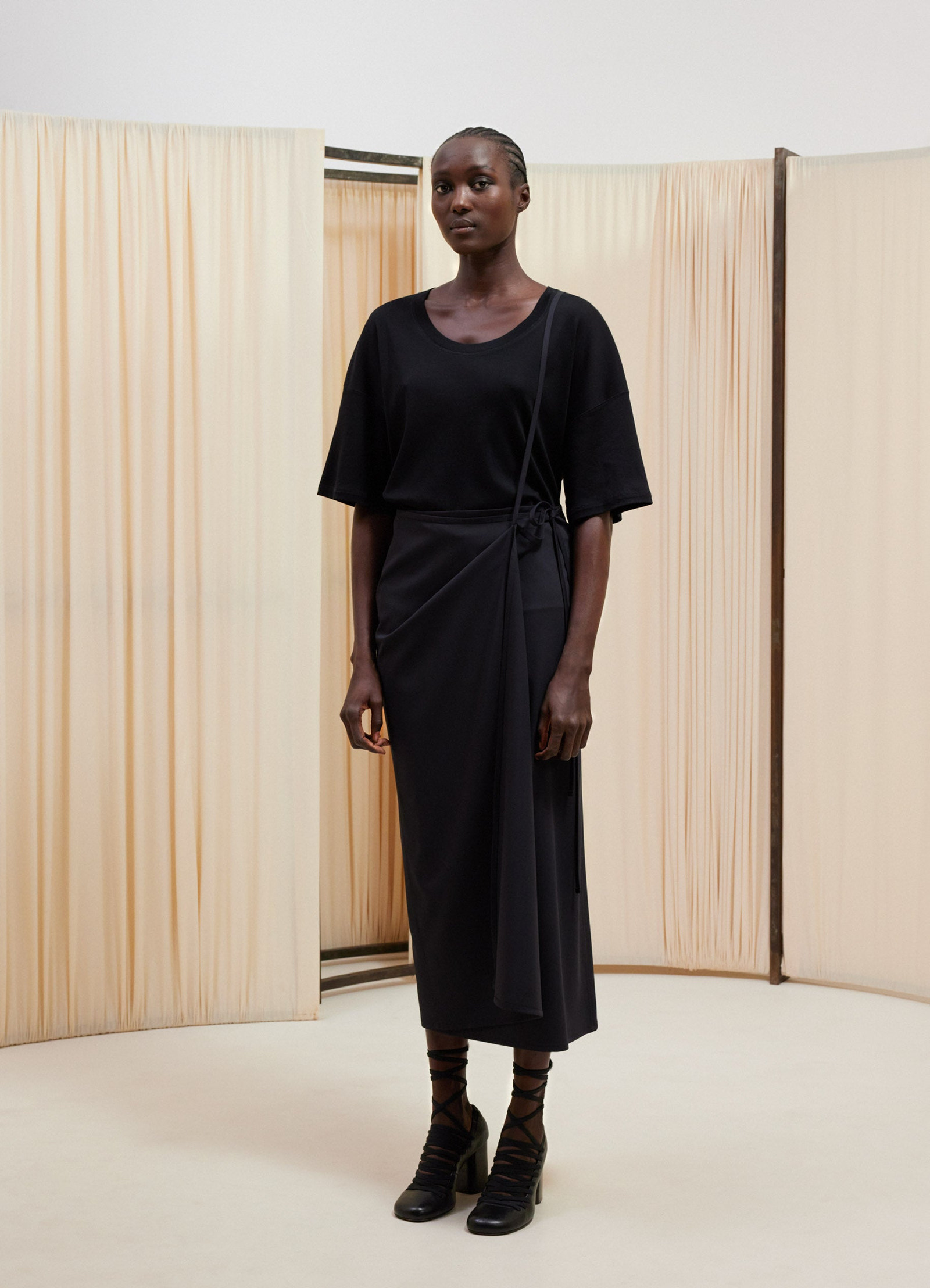 Lemaire rib t-shirt in black mid-weight jersey, model shot, three-quarter view knee-length drape skirt