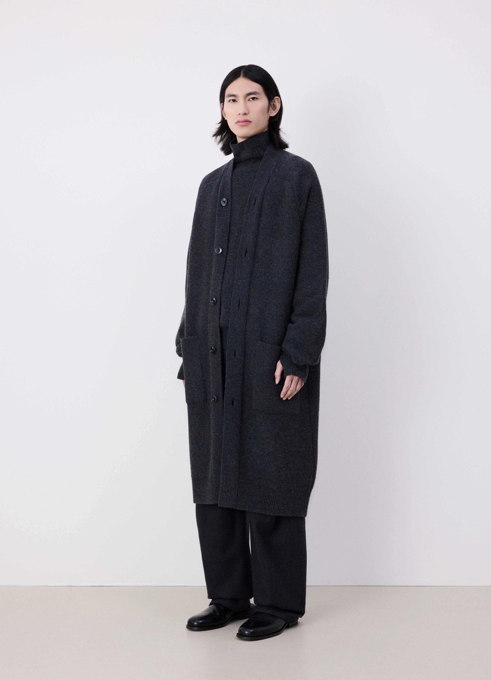 Lemaire long cardigan in dark lambswool, model shot, three-quarter view buttoned with pockets