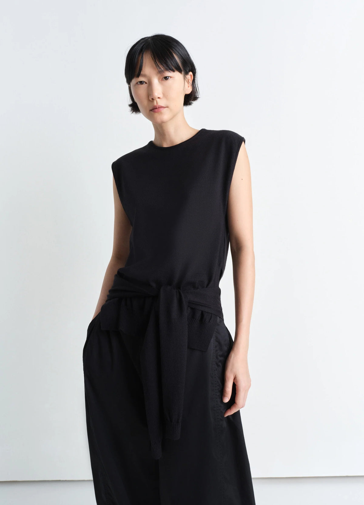 Trompe Loeil Sleeveless Jumper in Black Merino Wool Blend, model shot, Front view Sleeveless with waist ties