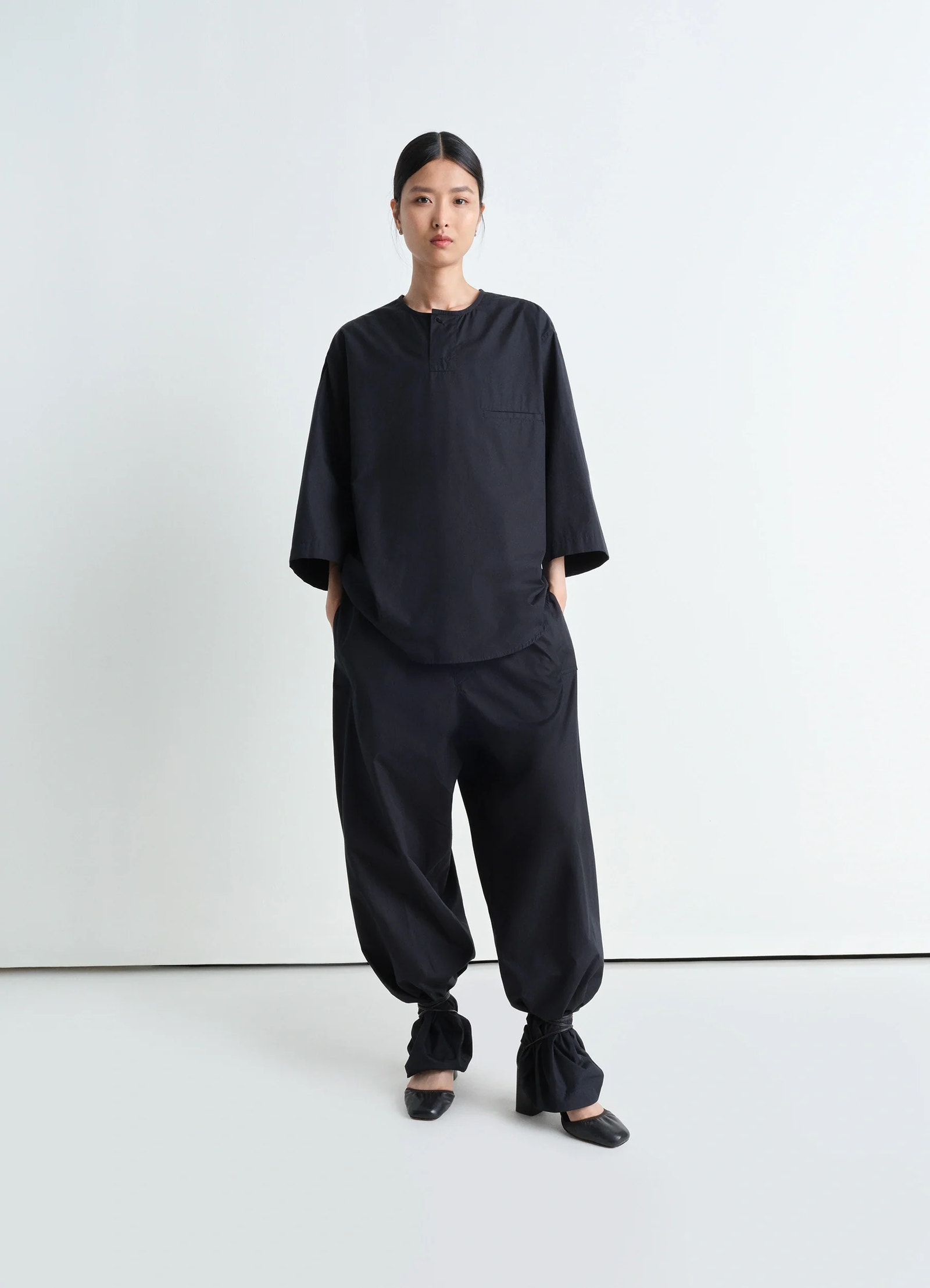 Short sleeve henley top in black heavy cotton poplin, model shot, full body front view oversized fit with high collar