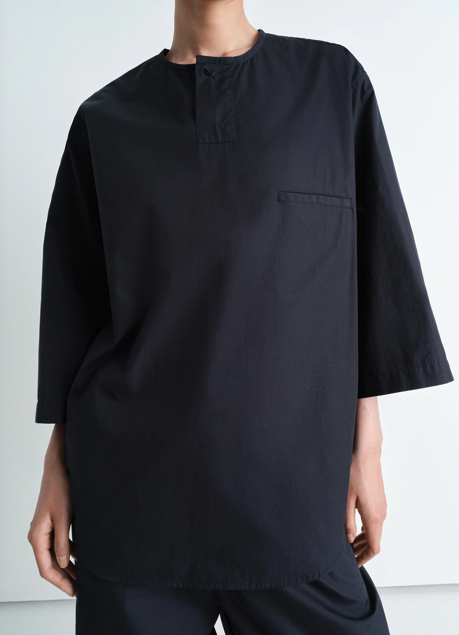 Short sleeve henley top in black heavy cotton poplin, model shot, close-up torso view hidden placket, chest pocket