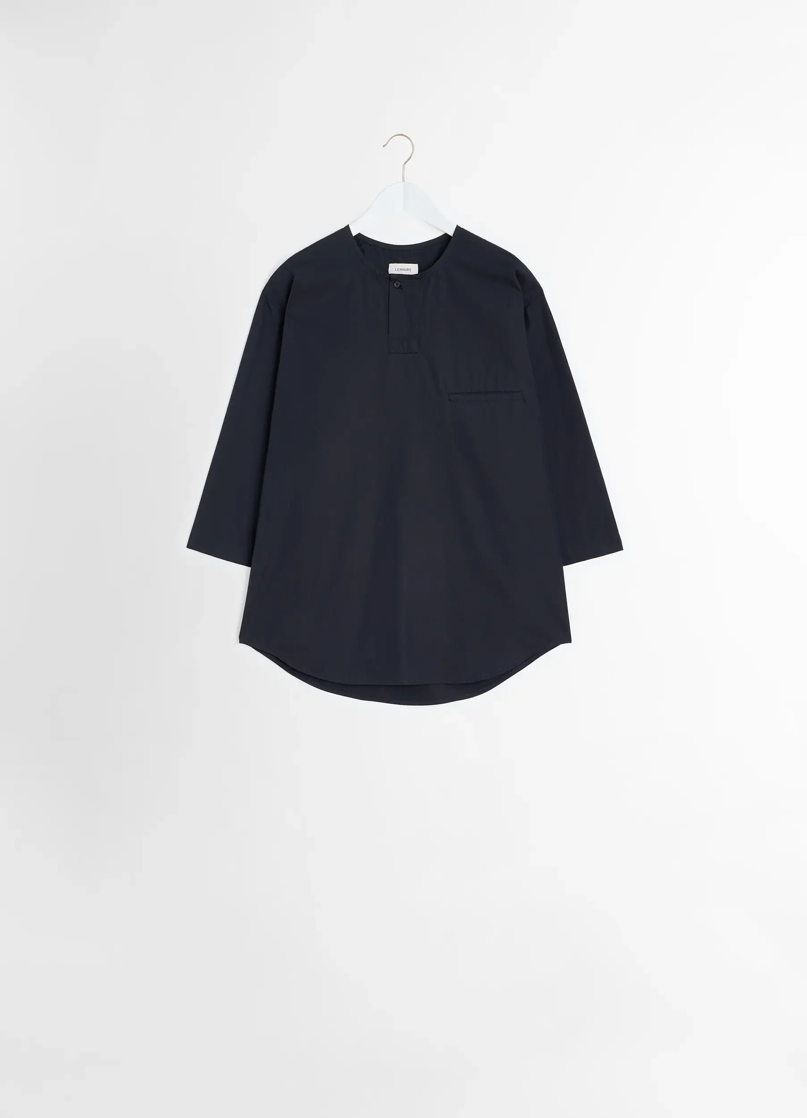 Short sleeve henley top in black heavy cotton poplin, product shot, hanging view curved hem detail