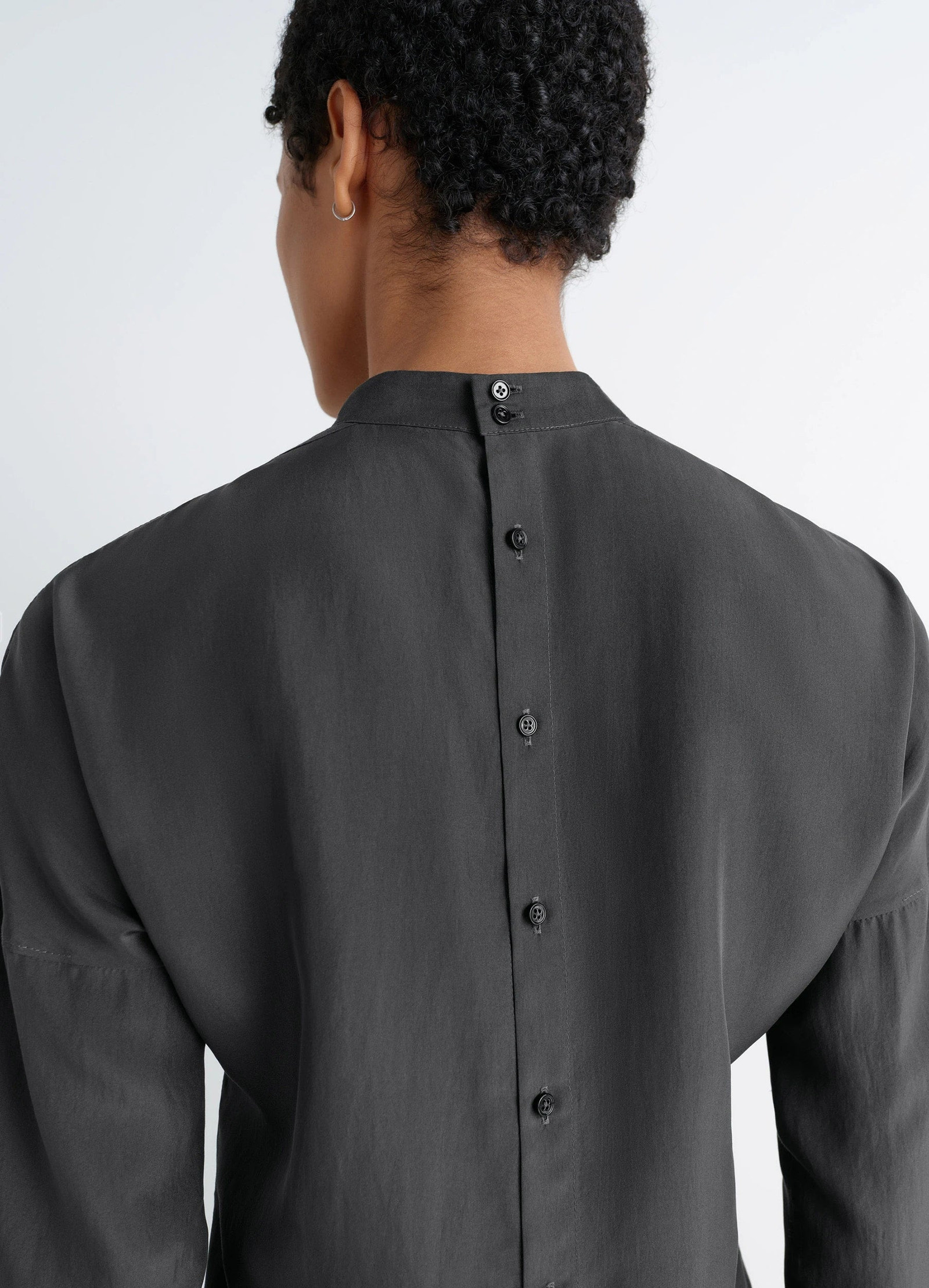 Light plastron top in black silk pongee, model shot, back detail view buttoned high neck