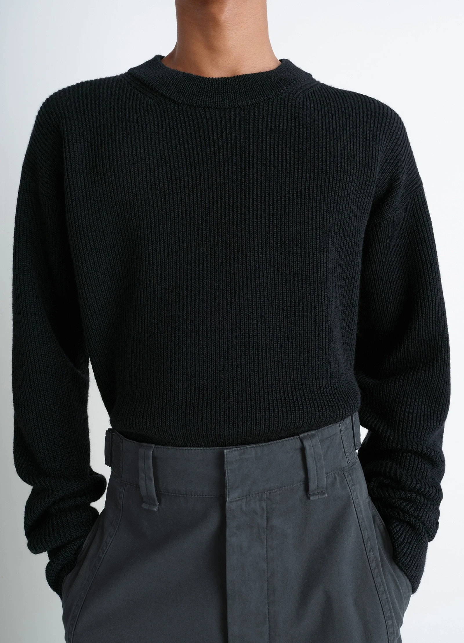 Boxy round neck sweater in ribbed virgin wool, model shot, close-up mid-section long sleeves visible