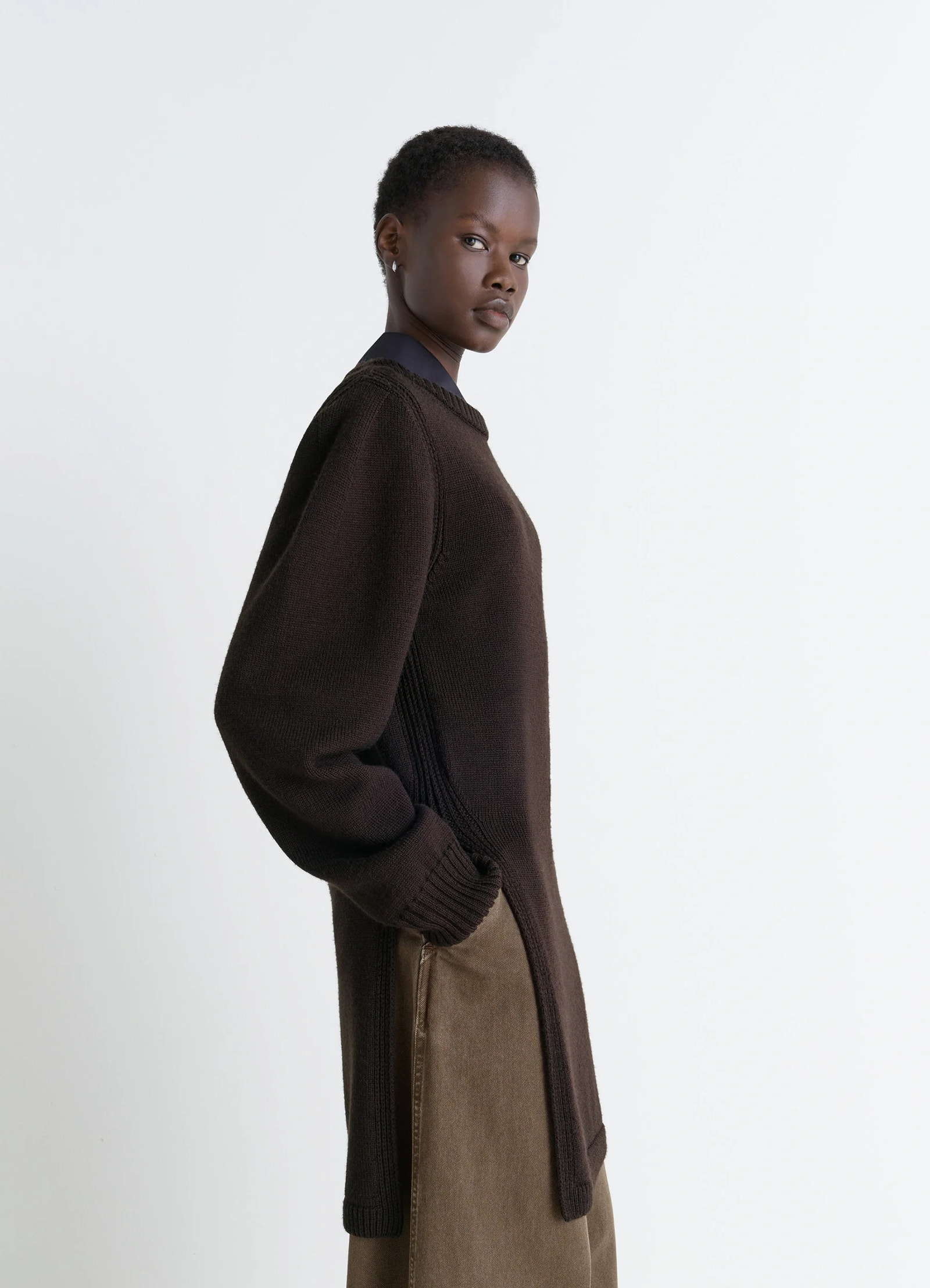 Sweater with slits in dark brown combed wool, model shot, side view soft texture, relaxed fit