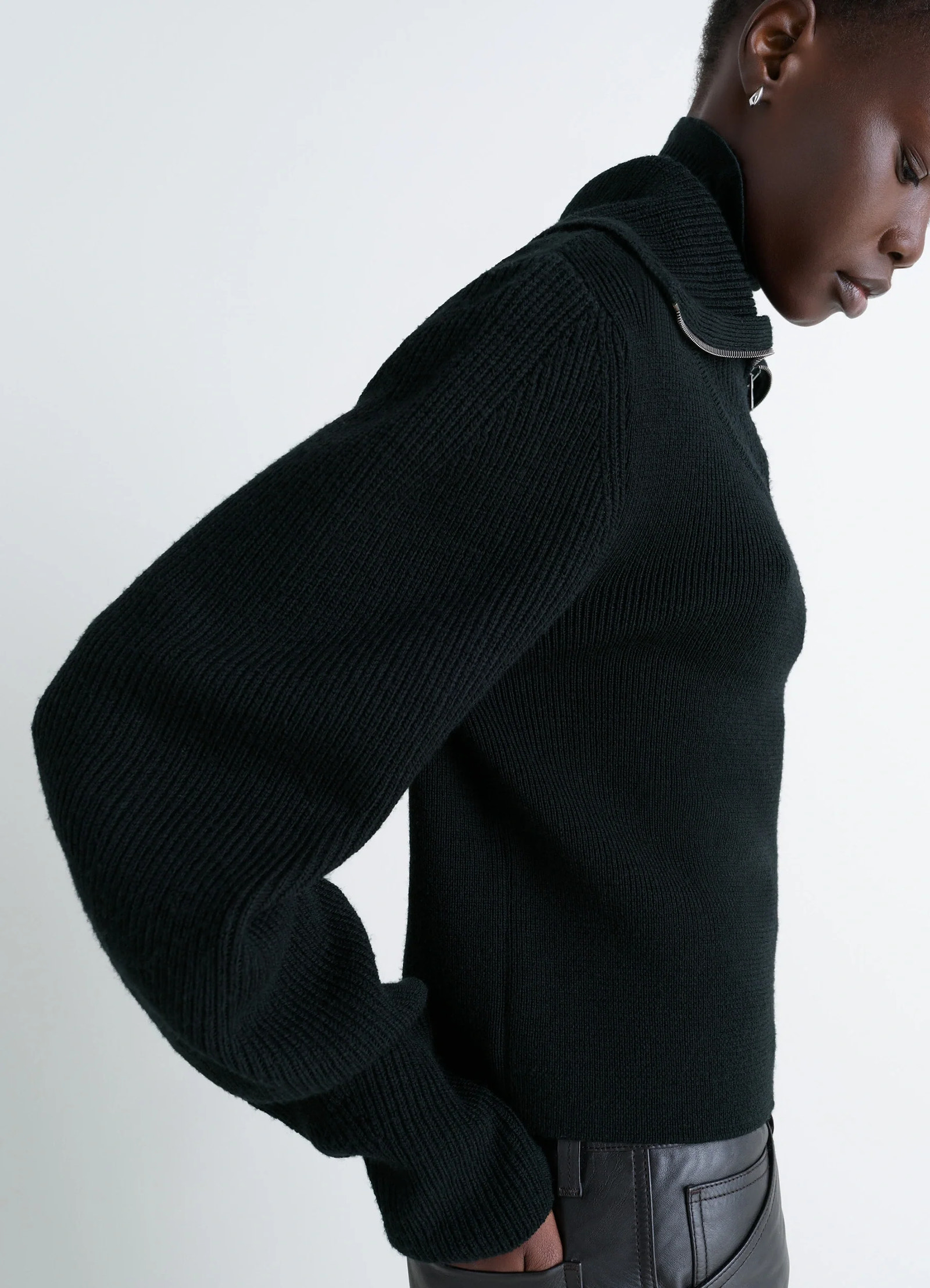 Zipped sweater in black combed wool, model shot, side profile view bulky sleeve silhouette