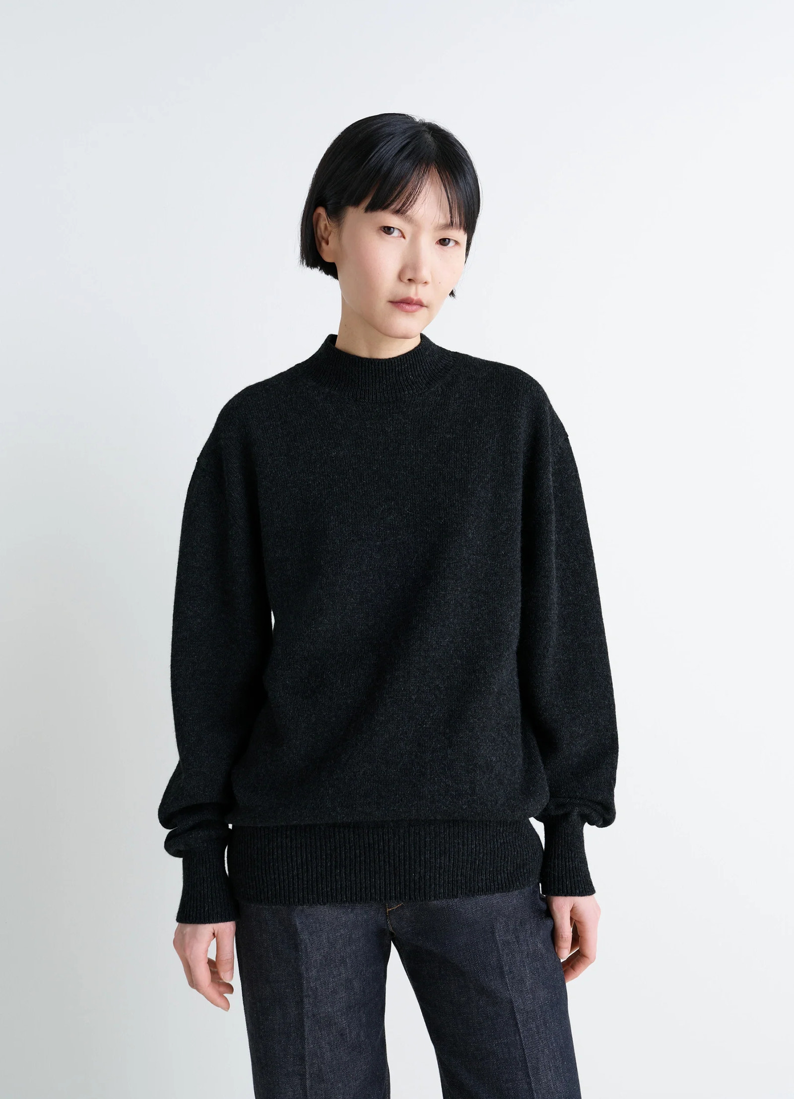 Mock neck sweater in black alpaca yak wool, model shot, three-quarter view ribbed cuffs and hem