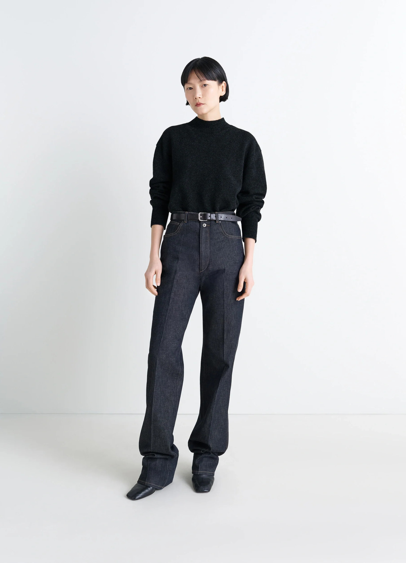 Mock neck sweater in black alpaca yak wool, model shot, side profile view tucked into high waist jeans