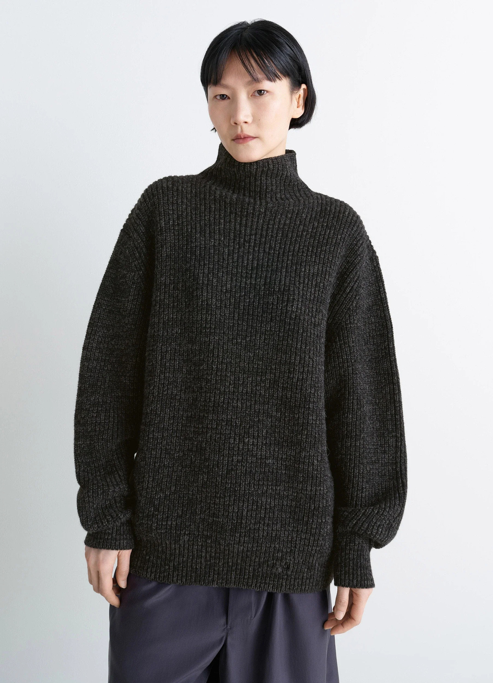 High neck sweater in densely ribbed alpaca yak, model shot, three-quarter view oversized sleeves
