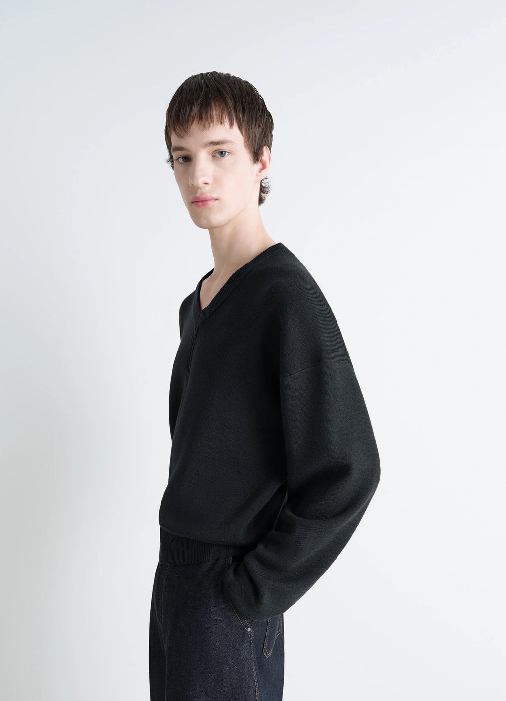 Lemaire V Neck Sweater in Blended Merino Wool in Black, model shot, side view ribbed hem