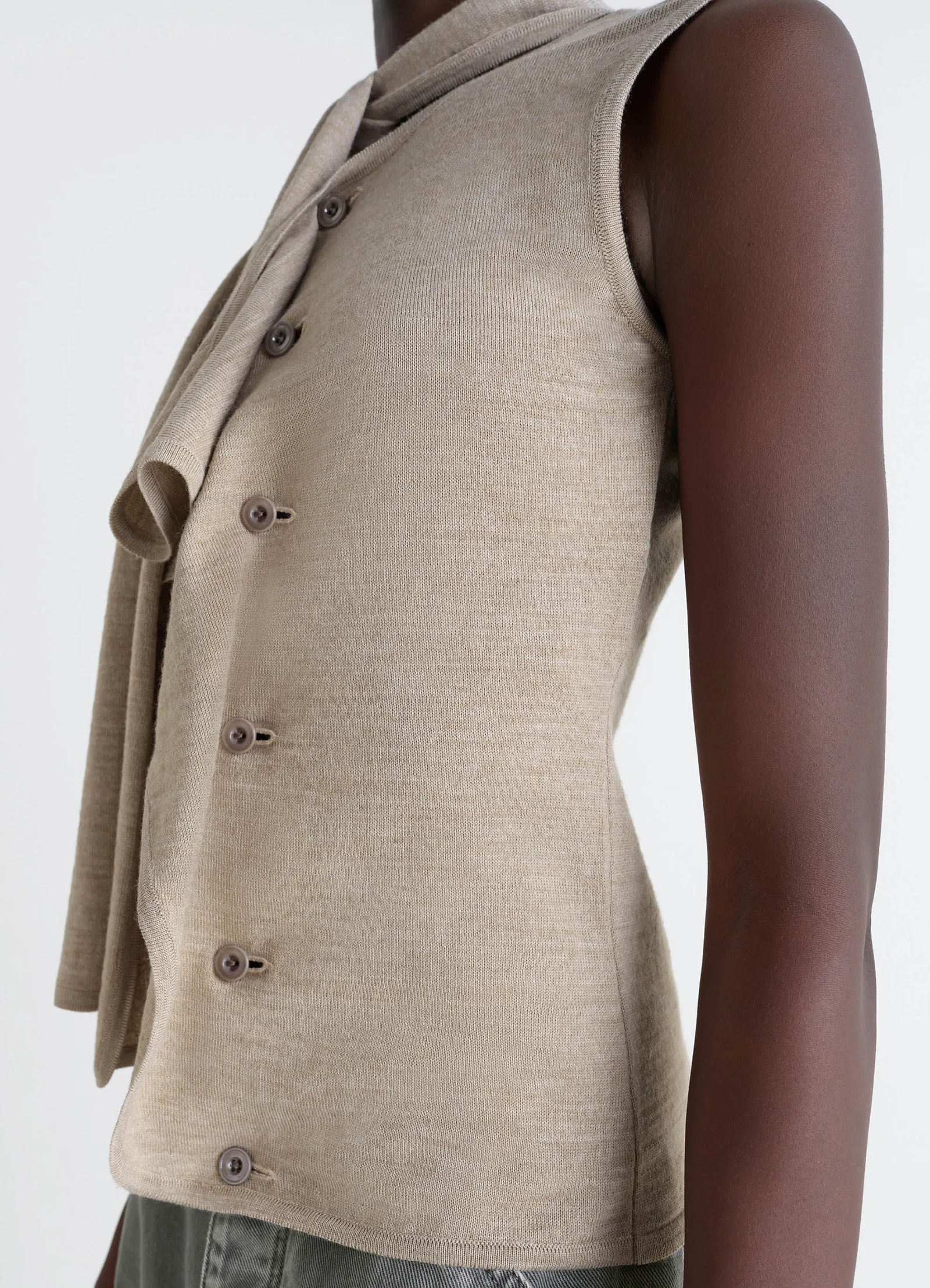 Lemaire asymmetrical sleeveless car in blended merino wool, model shot, close-up side detail buttoned closure sleeves