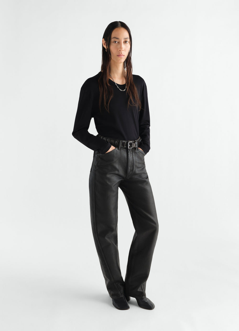Rib long sleeve black jersey top by LEMAIRE worn by model with black leather pants on white background