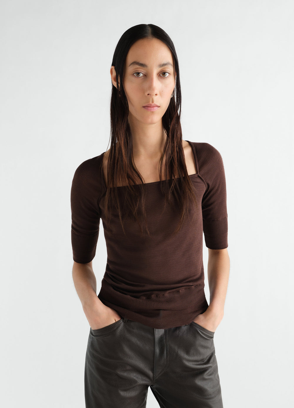 Three-quarter sleeve brown silk blend top by LEMAIRE worn by model front view with hands in pockets