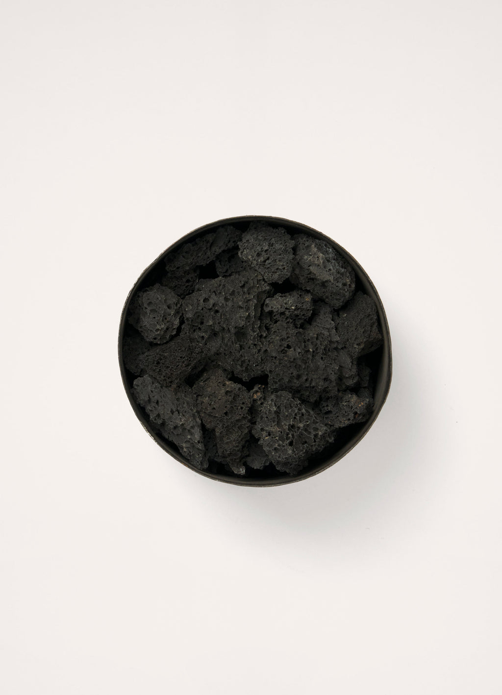 Mad et Len for Lemaire Bois d’Orage in Black Metal and Lava Stone, product shot, overhead view filled with lava stones