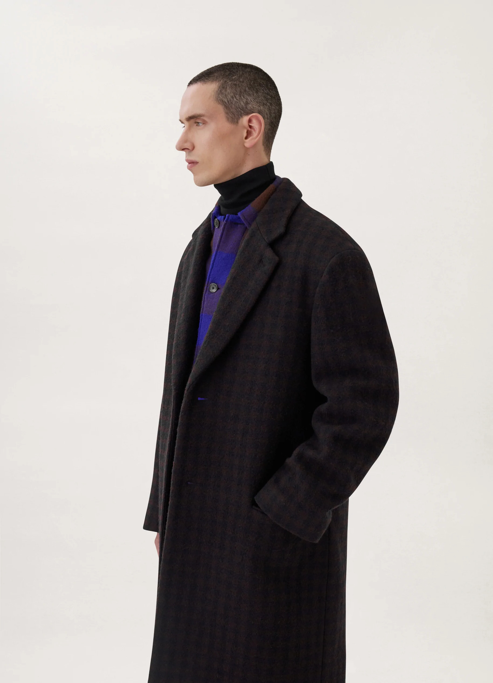 Lemaire chesterfield coat in brown/marine, model shot, right profile view hands-in-pocket, layered look
