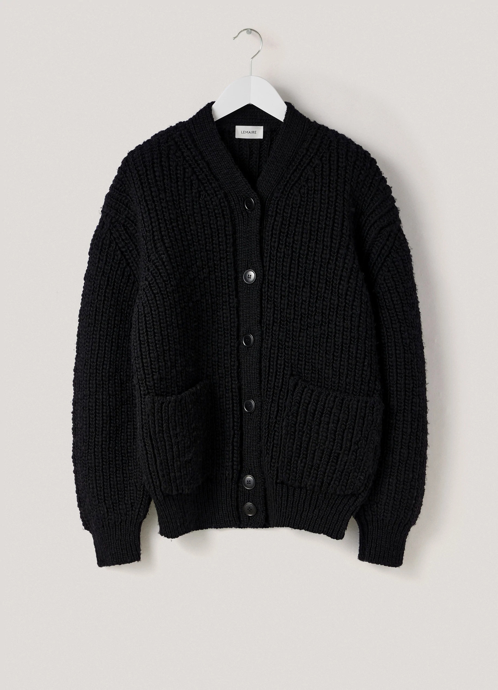 Chunky cardigan in black thick wool, product shot, packshot hanging view ribbed cuffs and hem