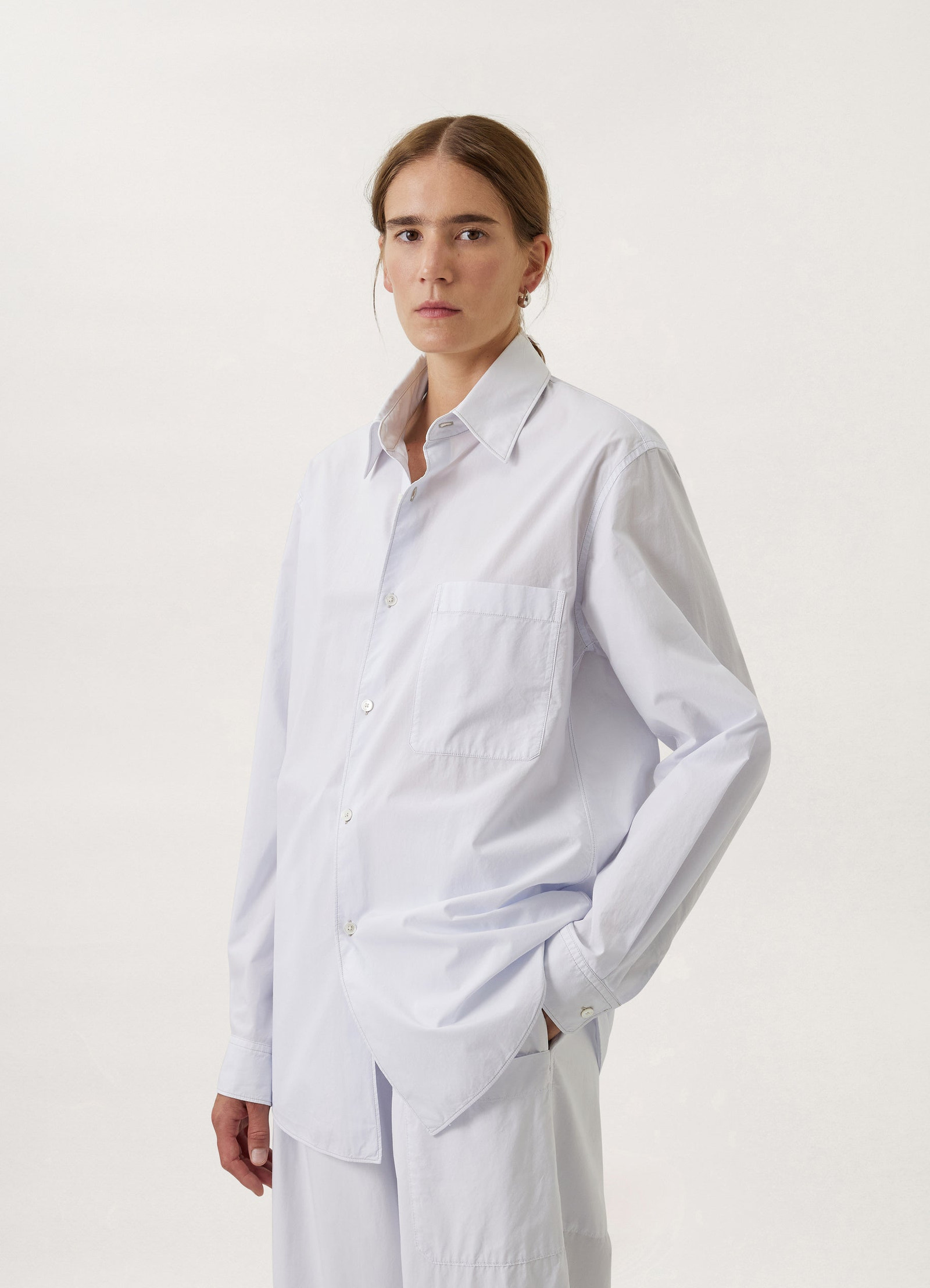 Lemaire regular long sleeve shirt in white compact cotton, model shot, over-the-shoulder view relaxed fit, right sleeve detai