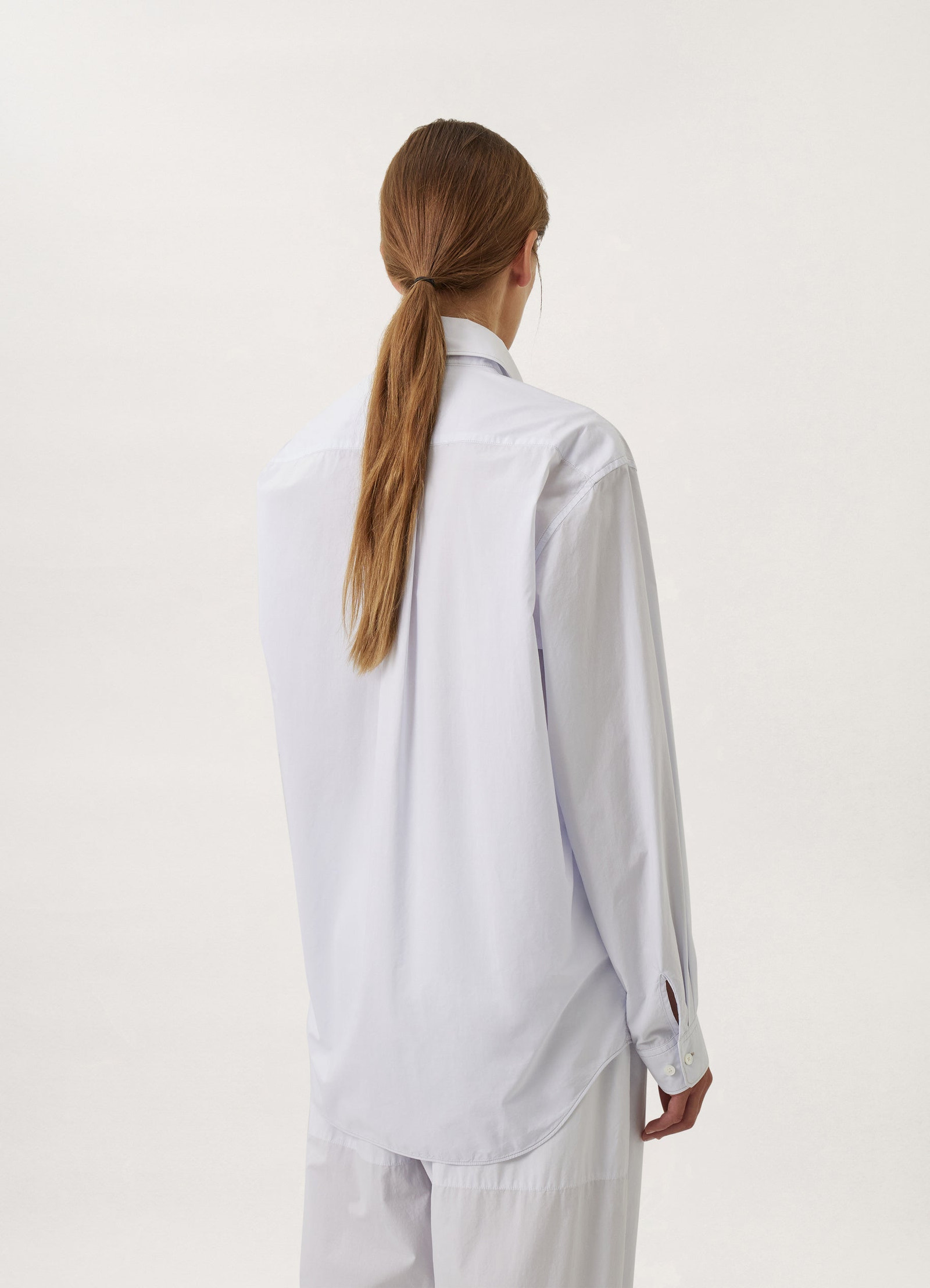 Lemaire regular long sleeve shirt in white compact cotton, model shot, rear even-shoulders view curved hem detail