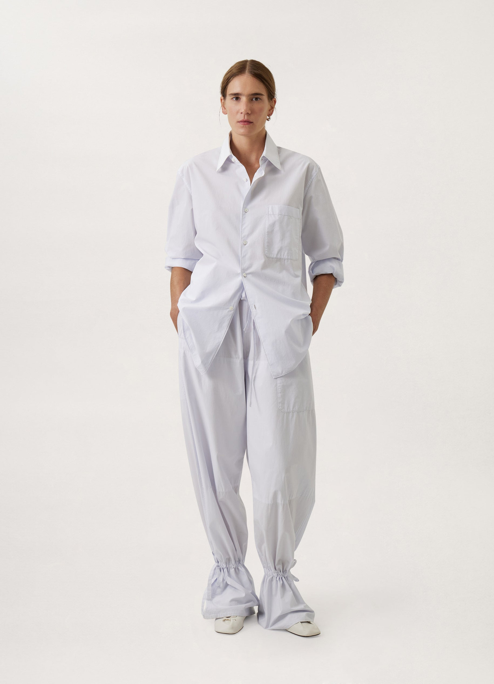 Lemaire regular long sleeve shirt in white compact cotton, model shot, waist-up front view rolled-up sleeves