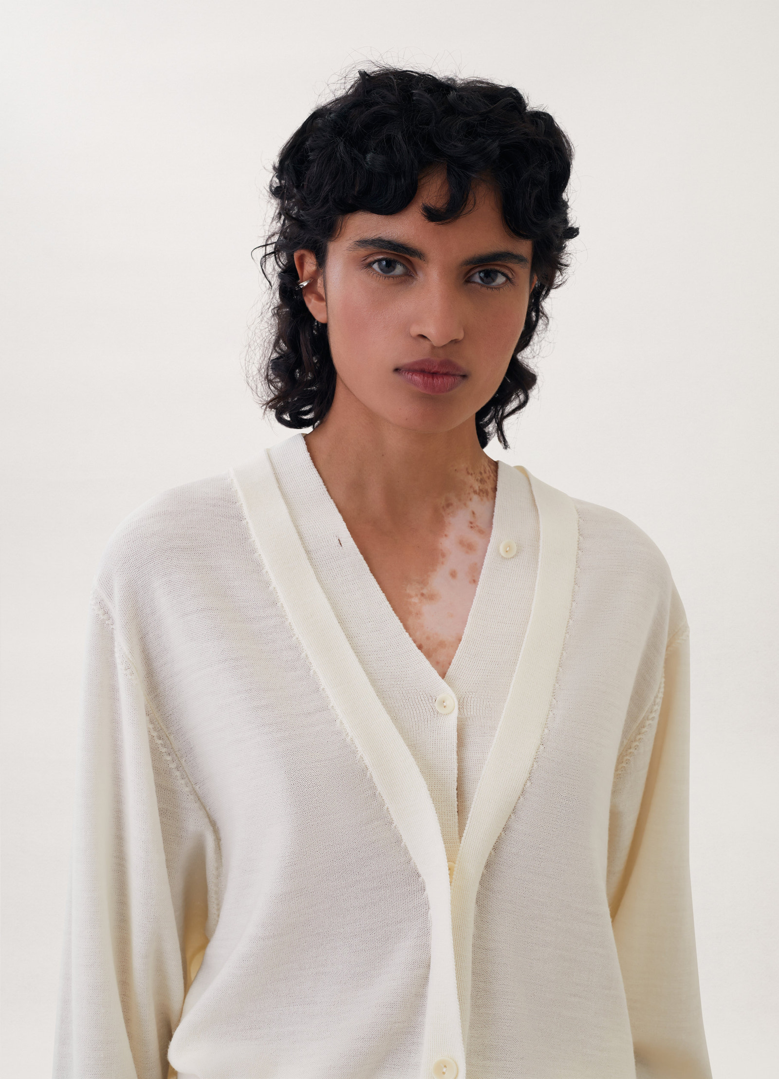 Trompe-l’oeil cardigan in cream knit, model shot, close-up view textured v-neck detail