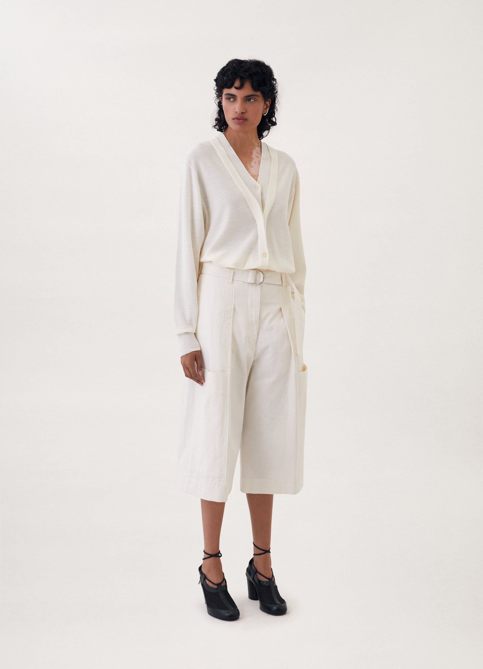 Trompe-l’oeil cardigan in cream knit, model shot, 3/4 side view long sleeves, soft drape