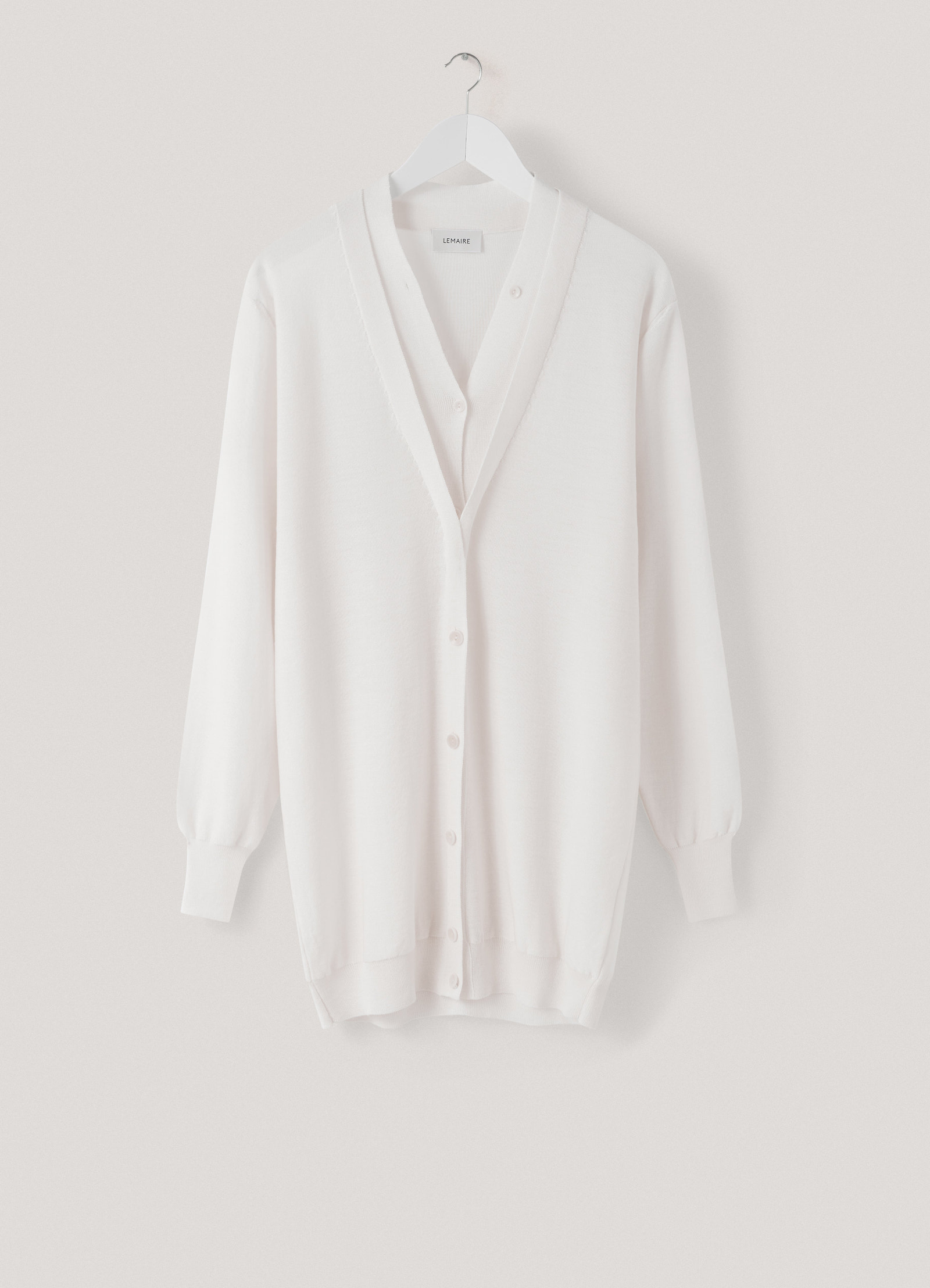 Trompe-l’oeil cardigan in cream knit, product shot, hanger display view ribbed cuffs and hem
